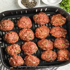 meatballs are being cooked in an air fryer with spices and seasonings on the side