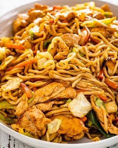 a white bowl filled with chicken lo mein noodles and veggies on a table