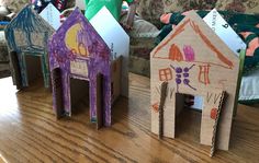 three houses made out of cardboard sitting on a table next to a couch and child's chair