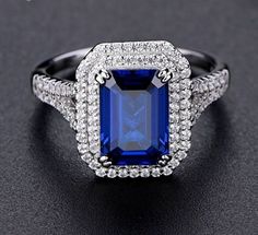 an engagement ring with a blue stone surrounded by white diamonds on a black surface,