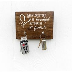 two keys hang from a wooden key holder with a sign that says every love story is beautiful but ours is my favorite