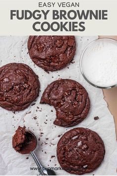 chocolate fudgey brownie cookies on parchment paper next to a glass of milk