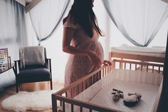 a pregnant woman standing next to a crib