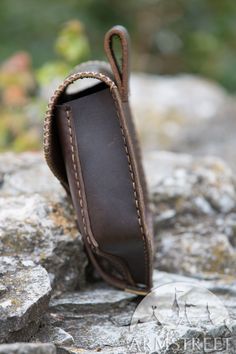 a brown leather case sitting on top of a rock