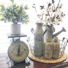 an arrangement of kitchen utensils and flowers on a table in front of a window