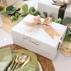 a white box with a bow on it sitting on top of a table next to silverware