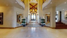 a large foyer with marble flooring and gold trimming on the walls, along with two staircases that lead up to the second floor