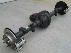 the front end of a vehicle with wheels and axles attached to it, sitting on concrete