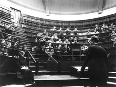 an old black and white photo of people in a library