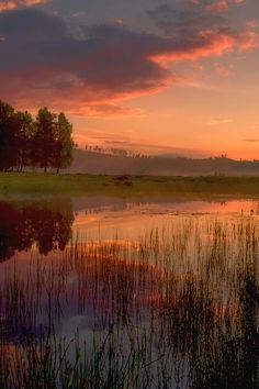 the sun is setting over a small lake