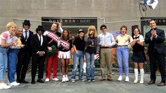 a group of people standing next to each other in front of a chain link fence