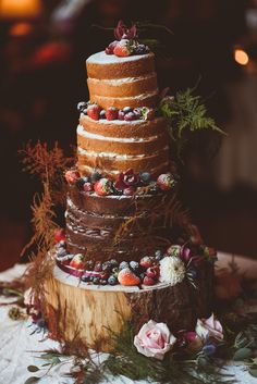 a multi layer cake sitting on top of a wooden table next to flowers and greenery