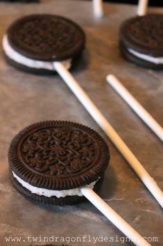 three oreo pops are sitting on top of each other with white sticks sticking out of them