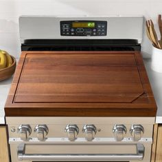 a stove top oven sitting inside of a kitchen next to a bowl of fruit on the counter