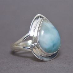 SKU: SS-058Material: 925 stamped sterling silverGemstone(s): Larimar (N)Gemstone Dimensions: 18 X 24 X 3 mmRing Size: US 9Weight: 7.0 gramsThis stunning Larimar ring features a large pear Larimar cabochon, set in a unique split bezel frame and a split shank ring. The split bezel frame adds the distinctiveness that makes this ring unique! The Larimar is a beautiful blend of ocean green and white waves. Teardrop Moonstone Ring In Sterling Silver, Sterling Silver Pear Ring Gift, Pear Shaped Sterling Silver Ring For Gift, Pear-shaped Sterling Silver Ring For Gift, Sterling Silver Teardrop Opal Ring, Silver Teardrop Opal Ring In Sterling Silver, Sterling Silver Teardrop Rings Stamped 925, Sterling Silver Teardrop Birthstone Gemstones, Teardrop Opal Ring In Sterling Silver