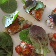 several small pieces of food with lettuce, tomatoes and other veggies