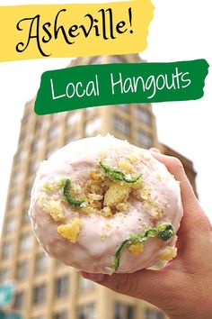 a person holding up a doughnut in front of a tall building with the words asherville local hangouts