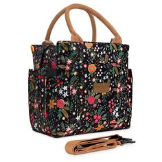 a black floral bag with brown handles and straps on the handle is next to a pair of scissors