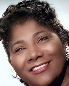 a close up of a person smiling with a necklace and earrings on her head,