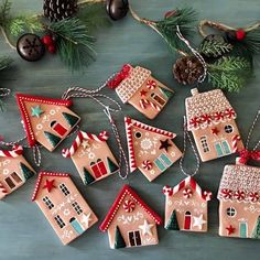 gingerbread houses decorated with red and green decorations on a table next to pine cones