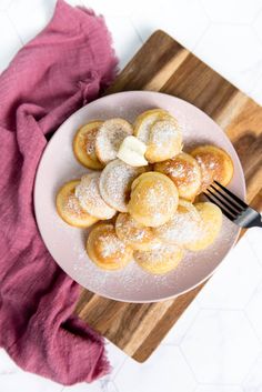 powdered sugar covered donuts on a plate with a fork