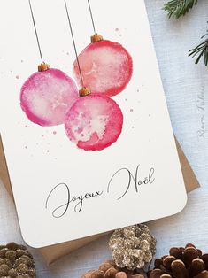 a christmas card with three ornaments hanging from it