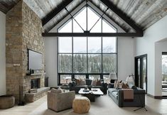 a living room filled with furniture and a large window covered in snow - capped mountains