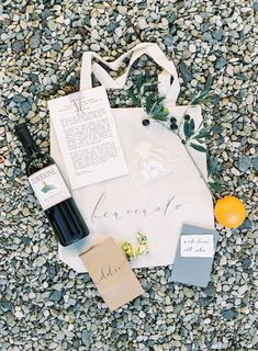 an assortment of personal items laid out on the ground next to a bag and wine bottle