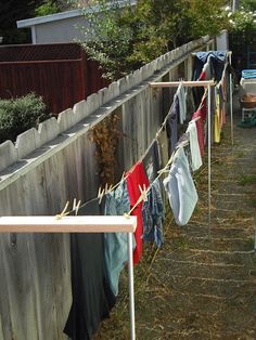 clothes hanging out to dry in the sun on a clothes line near a wooden fence