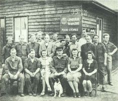 an old black and white photo of a group of people posing in front of a building