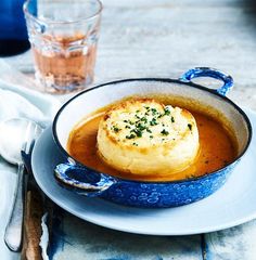 a bowl filled with soup on top of a table next to a fork and knife