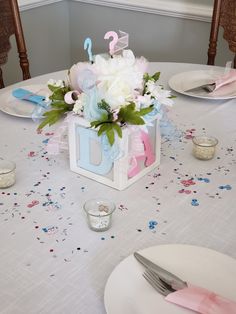 a table set with plates, silverware and pink and blue decorations for a birthday party