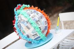 a paper mache sitting on top of a blue plate next to a white chair