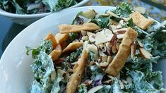 two white bowls filled with salad on top of a blue table cloth covered in food