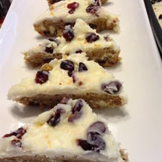 several pieces of cake sitting on top of a white platter with cranberry toppings