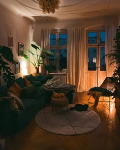 a living room filled with lots of furniture next to a large window covered in curtains