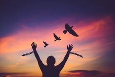 a man with his hands in the air and birds flying above him