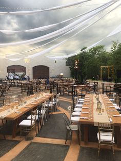 tables and chairs are set up for an outdoor event with white draping on the ceiling