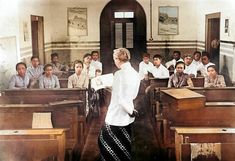 a woman standing in front of a classroom full of people wearing white shirts and black skirts