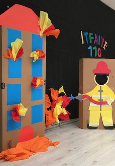 two cardboard boxes with paper cut out of them, one is holding a knife and the other is wearing a fireman's uniform