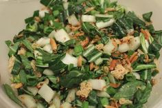 a bowl filled with vegetables and nuts on top of a table