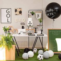 a soccer themed party with black and white decorations, balloons, and sports balls on the floor