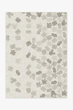 a white and gray rug with small flowers on it's side, in front of a light grey background