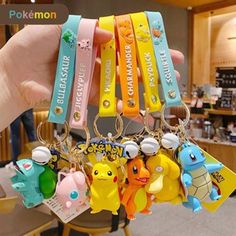 a person holding up several key chains with pokemon characters on them