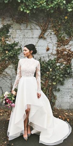 a woman standing in front of a wall wearing a white dress