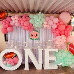 a table topped with lots of balloons and watermelon slices on top of it