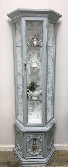 an old china cabinet with glass doors and silver trimmings on the top shelf