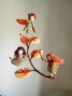 three little fairy dolls hanging from a tree branch