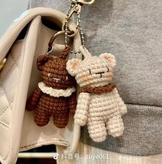 two crocheted teddy bears are attached to a purse keychain that is being held by someone's hand