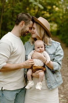 a man and woman holding a baby in their arms